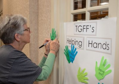 Family member writing donations on a “helping hands” poster